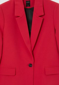 Blazer rosso con revers a freccia, chiusura a un bottone nero, due tasche anteriori a pattina e fodera interna nera, taglia piccola.