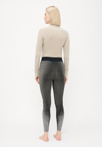 Lys grå langermet topp kombinert med svarte gradient tights som har et teksturert mønster, elastisk midje og slim fit.