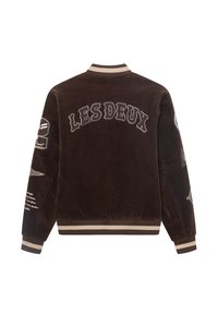 Brun kordjacka med kontrasterande beige ribbad krage och muddar. Har "LES DEUX" broderat på ryggen och olika lappar på ärmarna.