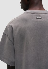 Szara bawełniana koszulka z luźnym krojem, szerokimi krótkimi rękawami i metką z tyłu z nazwą marki "WRSTBHVR."