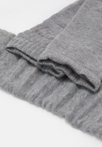 Grauer gestrickter Stoff mit geripptem Muster, der gefaltete Abschnitte aufweist. Weich und dehnbar, ideal zum Schichten bei kaltem Wetter.