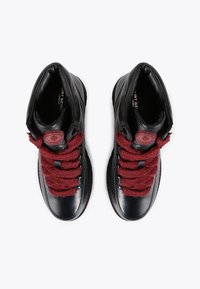 Czarne skórzane sneakersy typu high-top z burgundowymi teksturowanymi sznurowadłami, okrągłą czerwoną naszywką z logo oraz gładkim czubkiem.