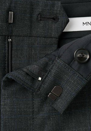 Czarne spodnie na miarę z subtelnym wzorem w kratę, zamkiem błyskawicznym i guzikem z teksturowanej tkaniny. Zawierają metalowe zapięcie i szlufki na pasek.