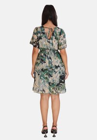 Robe à motifs floraux dans des tons de vert et de beige, avec des manches courtes, une taille cintrée et un dos en V profond.