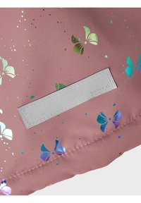 Tissu rose avec des imprimés de papillons holographiques et une étiquette rectangulaire réfléchissante cousue.