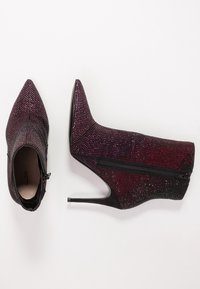 Stivaletti alla caviglia in paillettes nere e rosse lucide con punta appuntita e tacco a stiletto. Presentano una cerniera laterale per la chiusura. Texture liscia.