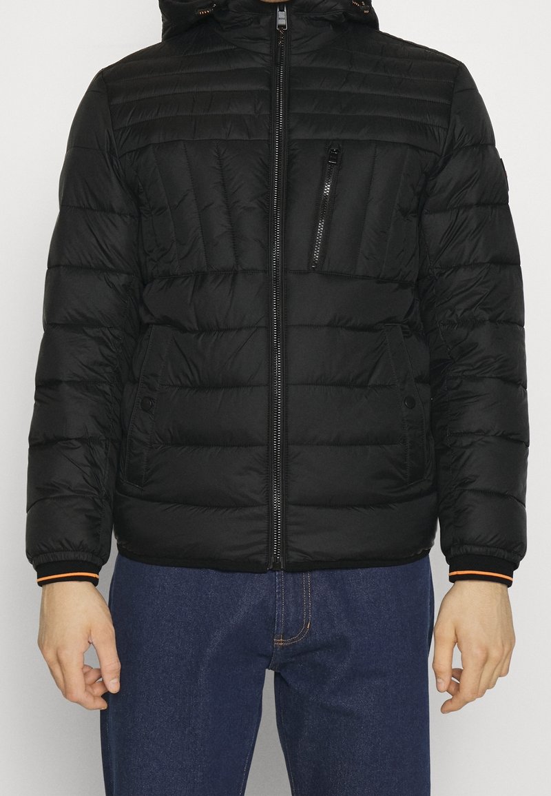 Czarna pikowana kurtka z zamkiem z przodu, wyposażona w odpinany kaptur, teksturowane panele oraz kontrastujące pomarańczowe akcenty na mankietach.