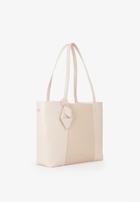 Borsa a spalla con un corpo in pelle crema liscia e un pannello in tessuto beige testurizzato. Le lunghe maniglie e un'etichetta staccabile aggiungono dettagli.