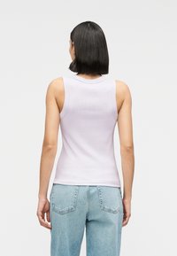 Απαλό λιλά ριμπ τοπ με στρογγυλή λαιμόκοψη και στενούς ιμάντες, σε συνδυασμό με ανοιχτό μπλε τζιν παντελόνι. Απλός σχεδιασμός, άψογη εφαρμογή χωρίς ραφές.