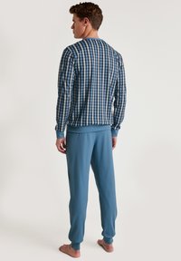 Langdurige blauwe en witte geblokte pyjama top gecombineerd met effen blauwe broek. Zacht katoen materiaal, relaxte pasvorm, ribgebreide manchetten en tailleband.