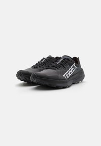Black running shoes with a mesh upper, featuring a padded collar, laces, and prominent "TERREX" branding on the side. Rubber outsole with traction.
