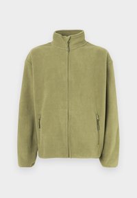 Olivovo zelená fleecová bunda s vysokým golierom, celopredným zipsom a dvoma vreckami na zips po bokoch. Mäkká textúra a voľný strih.