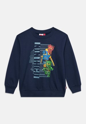 Sweat-shirt bleu marine pour enfants avec des personnages Ninjago en rouge, bleu et vert tenant des armes et le mot "NINJAGO" à la verticale à côté d’eux.