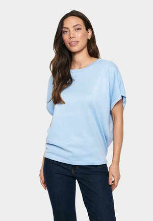 Camiseta de color azul claro, de corte holgado y mangas cortas, con una textura suave, escote redondo y un ajuste relajado, combinada con jeans oscuros.