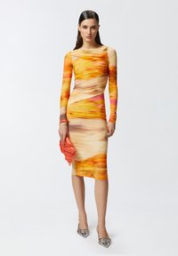 Kombinirana haljina dugih rukava koja se prianja uz tijelo u vrtložnom uzorku u narančastoj, žutoj i ružičastoj boji, s mekom teksturom i krojem do koljena. Uključuje narančastu torbicu.
