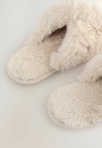Faux fur slippers in light beige with a soft, fluffy texture. Rounded toe design and simple fabric sole for comfort.