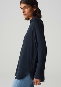 Maglietta a maniche lunghe blu navy con colletto a punta, vestibilità comoda e spacchi laterali, realizzata in tessuto morbido con polsini con bottoni.