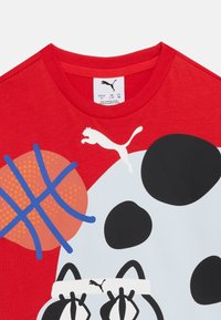 Κόκκινο παιδικό πουκάμισο με μεγάλο γραφικό μιας πάντα που φοράει λευκή κ ορδέλα και ένα μπάσκετ με μπλε γραμμές, με το λογότυπο της Puma.