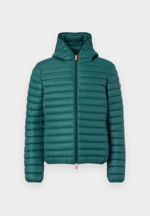 Turkooizen doorgestikte pufferjack met capuchon, ritssluiting aan de voorkant, elastische manchetten en kleine oranje ritstrekker tegen een effen witte achtergrond.