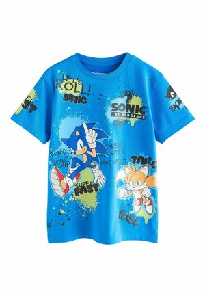 Blå bomullst-shirt med Sonic the Hedgehog och Tails. Grafiken inkluderar text och stänkmönster med livliga färger och lekfulla motiv.