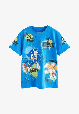 Modré bavlnené tričko s motívom Sonica the Hedgehoga a Taila. Grafika obsahuje text a škvrnité vzory s výraznými farbami a hravými obrázkami.