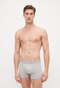 Graue Baumwoll-Boxershorts mit elastischem Bund und „JACK & JONES“-Logo. Glatte Textur und enganliegendes Design, das Modell steht vor einem weißen Hintergrund.