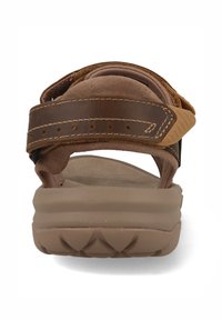 Bruine sandaal met een bovenwerk van suede en een dikke rubberen zool. Voorzien van verstelbare banden en een gevoerde voetbed voor comfort.