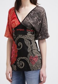 Top Multicolor de Desigual con escote en V profundo, base negra, mangas estampadas en rojo y gris, y diseños y acentos dorados intrincados.