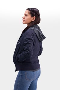 Marineblaues Bomberjacke mit grauem Kapuzen, ausgestattet mit einem Reißverschluss vorne, seitlichen Taschen und gerippten Bündchen, kombiniert mit blauen Jeans.