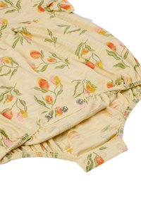 Combinaison jaune avec un motif floral en rose, orange et vert. Comprend des fermetures à pression en bas et un tissu doux et texturé.