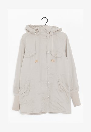 Chaqueta beige con capucha, hecha de tela ligera. Cuenta con bolsillos tipo canguro y detalles con botones. Puños elásticos con cordón ajustable alrededor de la capucha.