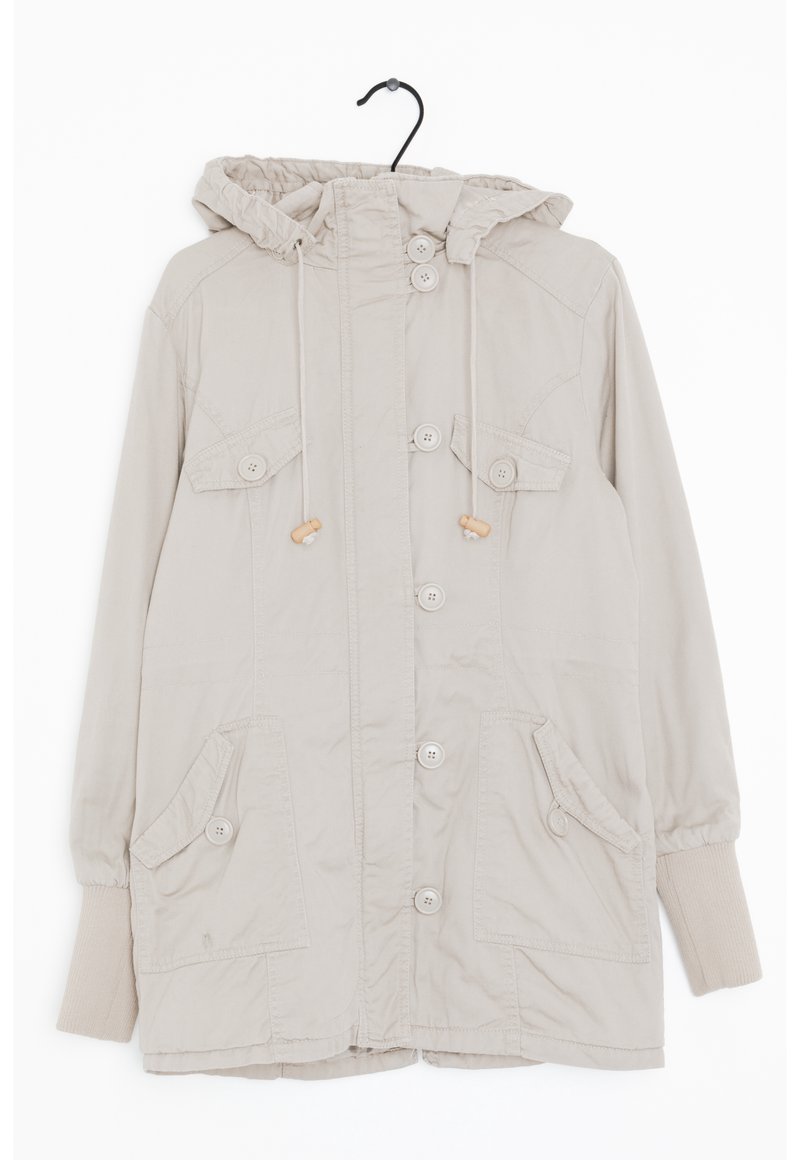 Beige hujacka i lätt tyg. Har kängurufickor och knapprader. Elastiska ärmslut och dragsko runt huvan.