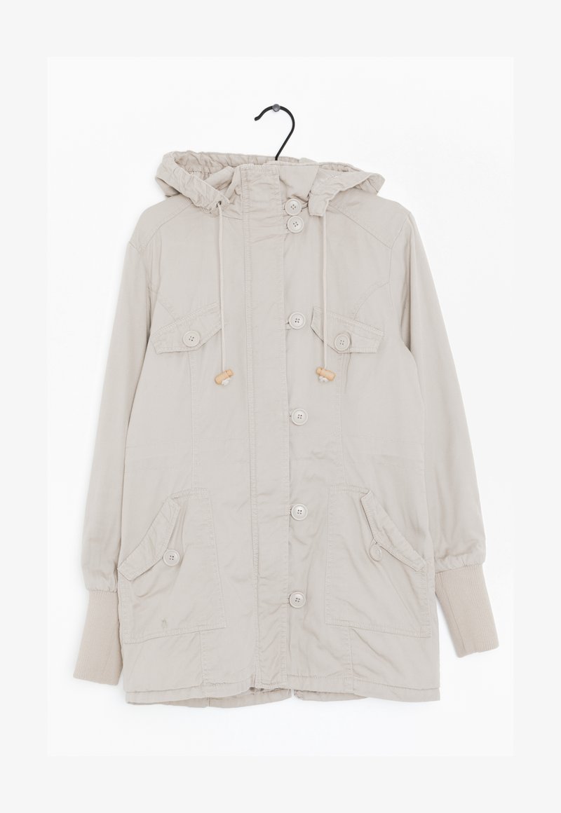 Beige hujacka i lätt tyg. Har kängurufickor och knapprader. Elastiska ärmslut och dragsko runt huvan.