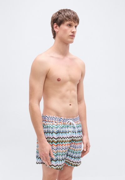 Shorts de bain à motif zigzag multicolore, fabriqués en tissu léger. Ils disposent d'une taille élastique avec cordon de serrage.