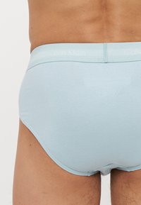 Svijetloplave pamučne gaćice s teksturiranim elastičnim pojasom na kojem se nalazi logo "Calvin Klein". Glatka tkanina s uskim krojem i minimalnim dizajnom.