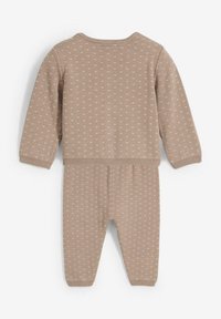 Set a due pezzi beige lavorato a maglia con maniche lunghe, polsini elasticizzati e un delicato motivo a cuore su tutta la superficie. Texture morbida, design casual.