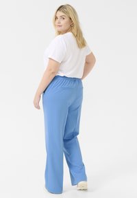 Light blue wide-leg pants with an elastic waistband and back pockets, paired with a plain white T-shirt, viewed from the back.