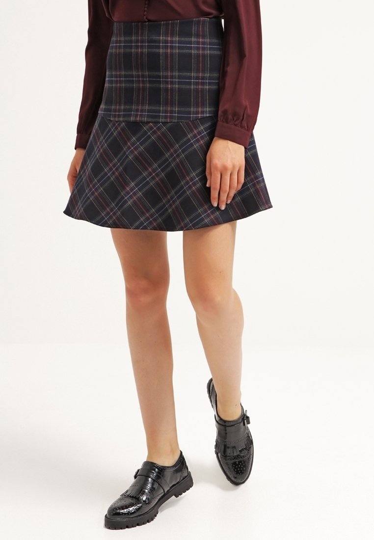 Marinrandig kjol med en figurnära midja och utsvängd nederdel. Tyget har en slät struktur med kontrasterande färger i mönstret. Svarta skor fulländar looken.