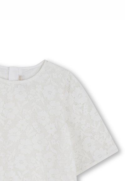 Haut en dentelle blanche avec motifs floraux, manches courtes et encolure ronde. Présente une texture délicate et un éclat subtil.
