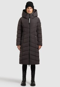 Pikk, tumedat halli värvi sulejope chevron-mustriga, täis lukk, suur kapuuts ja küljel taskud. Kandke koos mustade pükste ja pahkluukinnastega.