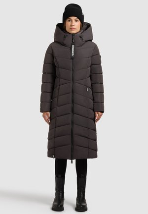 Pikk, tumedat halli värvi sulejope chevron-mustriga, täis lukk, suur kapuuts ja küljel taskud. Kandke koos mustade pükste ja pahkluukinnastega.