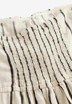 Tissu de couleur claire avec des rayures noires, présentant une texture froncée et des détails élastiques à l'arrière, s'évaporant en un ourlet plissé.