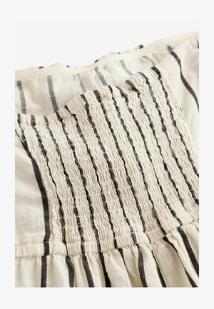 Vaalean värinen kangas mustilla raidoilla, jossa on kerättyä tekstiiliä ja joustava yksityiskohta takana, virtanena laskostettuun helmaan.