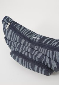 Pochette a strisce zebrate blu con due scomparti con zip, realizzata in tessuto testurizzato, con accenti blu navy e un design curvo.