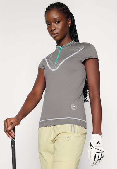 Gray golf shirt with a round neck and a turquoise zipper, featuring a subtle pattern on the front. Paired with light yellow pants and a white glove.