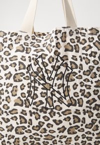Plátěná taška s béžovým a hnědým leopardím potiskem. Na přední straně se nachází černě vyšitý logo "NY". K dispozici jsou pevné úchyty.
