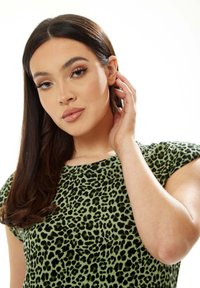 Green leopard print top with short sleeves, smooth texture, fitted design, featuring a bold black pattern on a light green background.