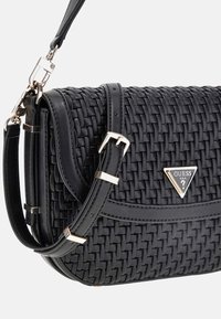 Sac à main tissé noir avec une bandoulière en cuir lisse et des garnitures en métal doré. Présente un accent de logo triangulaire et une attache à boucle sécurisée.