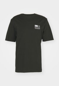 Camiseta de algodón negra con cuello redondo. Presenta un estampado gráfico blanco en el lado izquierdo del pecho, incluyendo el texto "CORE-TG TECHNOLOGY" y lunares.