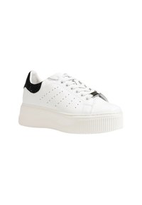 Sneaker bianca con una robusta piattaforma, caratterizzata da un tallone nero testurizzato, design perforato sui lati e dettagli in metallo sui passanti per i lacci.